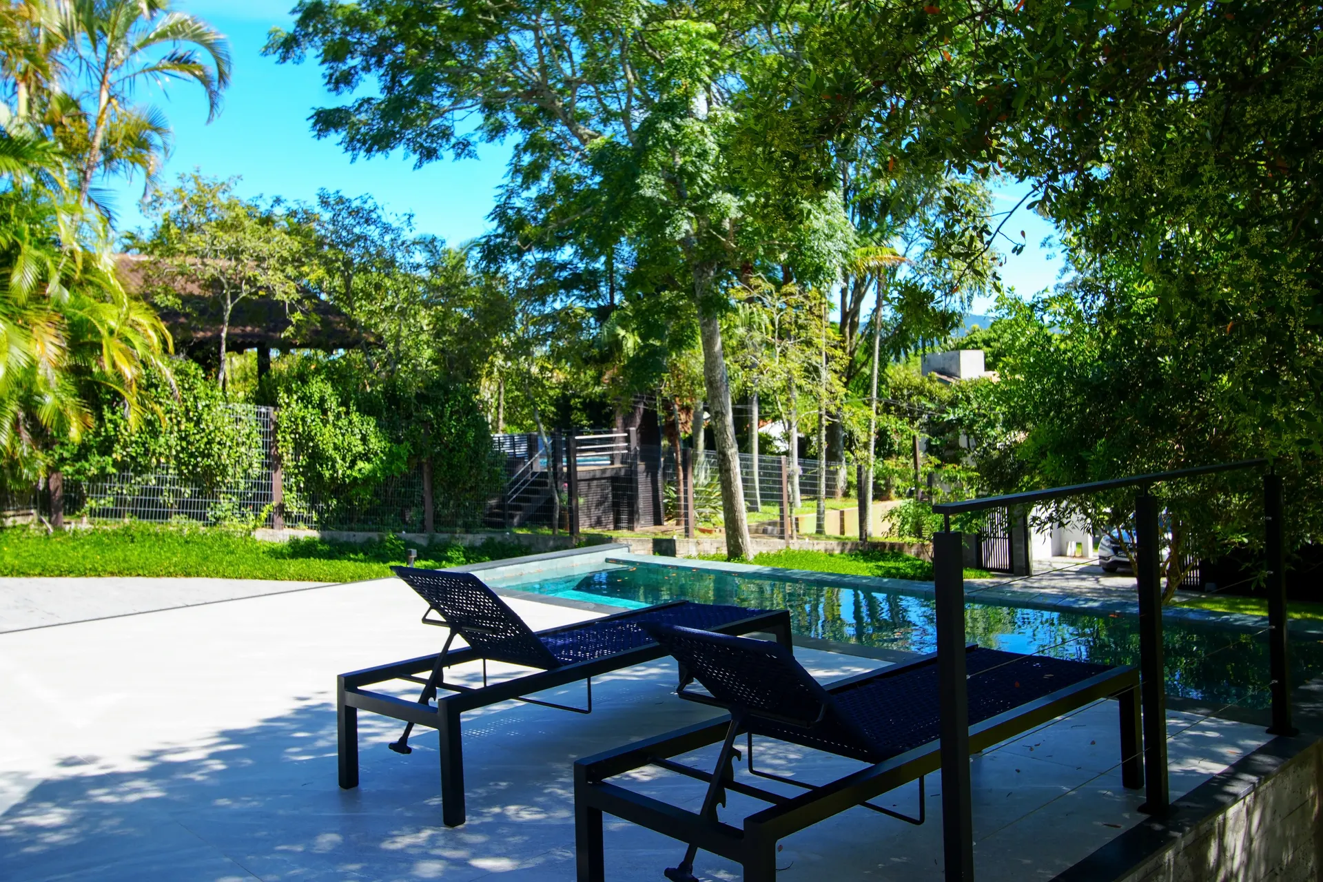 Jardim tropical com piscina e espreguiçadeiras
